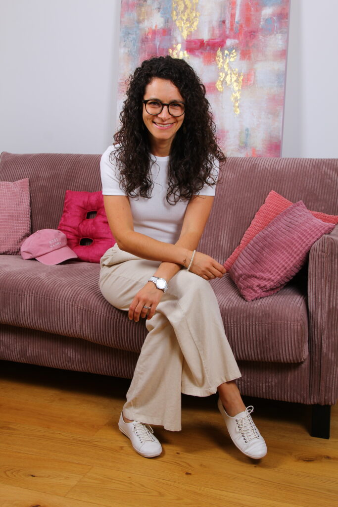 Portrait im Sitzen auf rosa Couch von Barbara Weißensteiner sie ist Strömerin für Strömen, Energie-Strömen und Impuls-Strömen